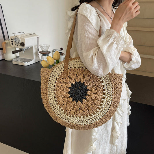 Round one shoulder straw bag with crochet design in brown, cream, and black, featuring single strap and no lining.