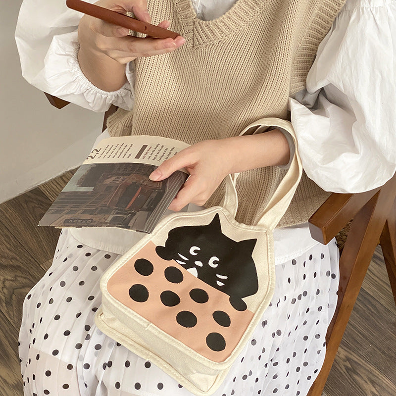 Casual hand-carrying canvas bag with cute kitten illustration.