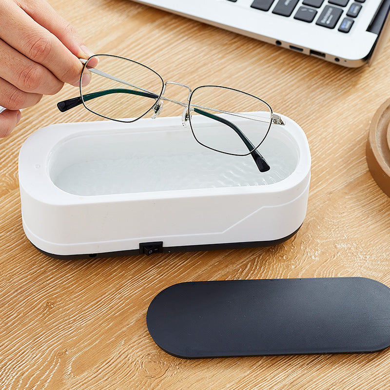 Ultrasonic eyeglasses cleaner in use on wooden table.